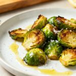 Air fryer crispy Brussels sprouts with golden caramelized Brussels sprouts, crispy browned edges, flaky sea salt, rosemary, and olive oil, served as a healthy vegetable side dish.
