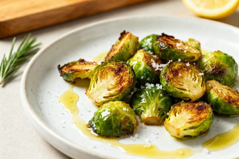 Air fryer crispy Brussels sprouts with golden caramelized Brussels sprouts, crispy browned edges, flaky sea salt, rosemary, and olive oil, served as a healthy vegetable side dish.