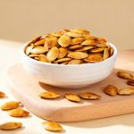 Air fryer pumpkin seeds with crispy golden roasted pumpkin seeds, savory seasoning, and a crunchy texture, served in a white bowl as an easy homemade snack.