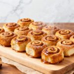 Air fryer cinnamon roll bites with soft fluffy cinnamon rolls, sweet cinnamon sugar filling, warm icing glaze, and steam rising, served as an easy breakfast or dessert.
