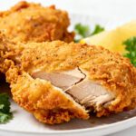 Air fryer buttermilk fried chicken with a crispy golden seasoned coating, juicy tender chicken, fresh parsley, and lemon wedges, served as a comforting homemade dinner.