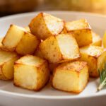 Air fryer potato cubes with crispy golden roasted potatoes, fluffy tender centers, fresh rosemary, and lemon wedges, served as an easy comforting side dish.