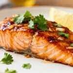 Air fryer honey garlic salmon with flaky tender salmon, a glossy honey garlic glaze, minced garlic, fresh parsley, and lemon wedges, served as an easy weeknight seafood dinner.