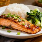Air fryer Asian salmon with flaky tender salmon glazed in a savory Asian sauce, sesame seeds, green onions, steamed rice, and bok choy, served as an easy weeknight dinner.