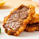 Air fryer crispy beef with a crunchy golden coating, juicy tender beef, fresh parsley, and lemon wedges, served as an easy high protein dinner or appetizer.