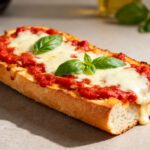 Air fryer French bread pizza with crispy toasted French bread, rich marinara sauce, gooey melted mozzarella cheese, and fresh basil, served as an easy homemade pizza.