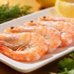 Air fryer frozen raw shrimp with juicy tender shrimp, simple seasoning, fresh herbs, lemon wedges, and coarse sea salt, served as an easy high protein seafood meal.
