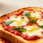 Air fryer pizza toast with crispy toasted bread, rich marinara sauce, gooey melted mozzarella cheese, fresh basil, and olive oil, served as an easy homemade lunch or snack.