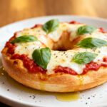 Air fryer bagel pizza with a crispy toasted bagel, rich marinara sauce, gooey melted mozzarella cheese, fresh basil, and olive oil, served as an easy homemade lunch or snack.