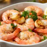 Air fryer garlic shrimp with juicy tender shrimp, roasted garlic cloves, fresh parsley, and lemon wedges, served as an easy high protein seafood dinner.