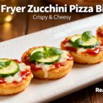 Air fryer zucchini pizza bites with tender zucchini rounds, rich marinara sauce, gooey melted mozzarella cheese, fresh basil, and zucchini slices, served as a healthy low carb snack.