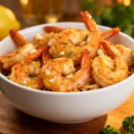 Air fryer shrimp scampi with juicy garlic butter shrimp served over pasta, fresh parsley, minced garlic, and lemon wedges, served as an easy seafood dinner.