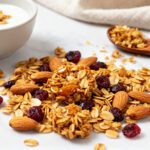 Air fryer homemade granola with toasted rolled oats, crunchy almonds, dried cranberries, and golden clusters, served as an easy healthy breakfast or snack.