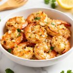 Air fryer garlic Parmesan shrimp with juicy tender shrimp, roasted garlic, grated Parmesan cheese, fresh parsley, and lemon wedges, served as an easy high protein seafood dinner.