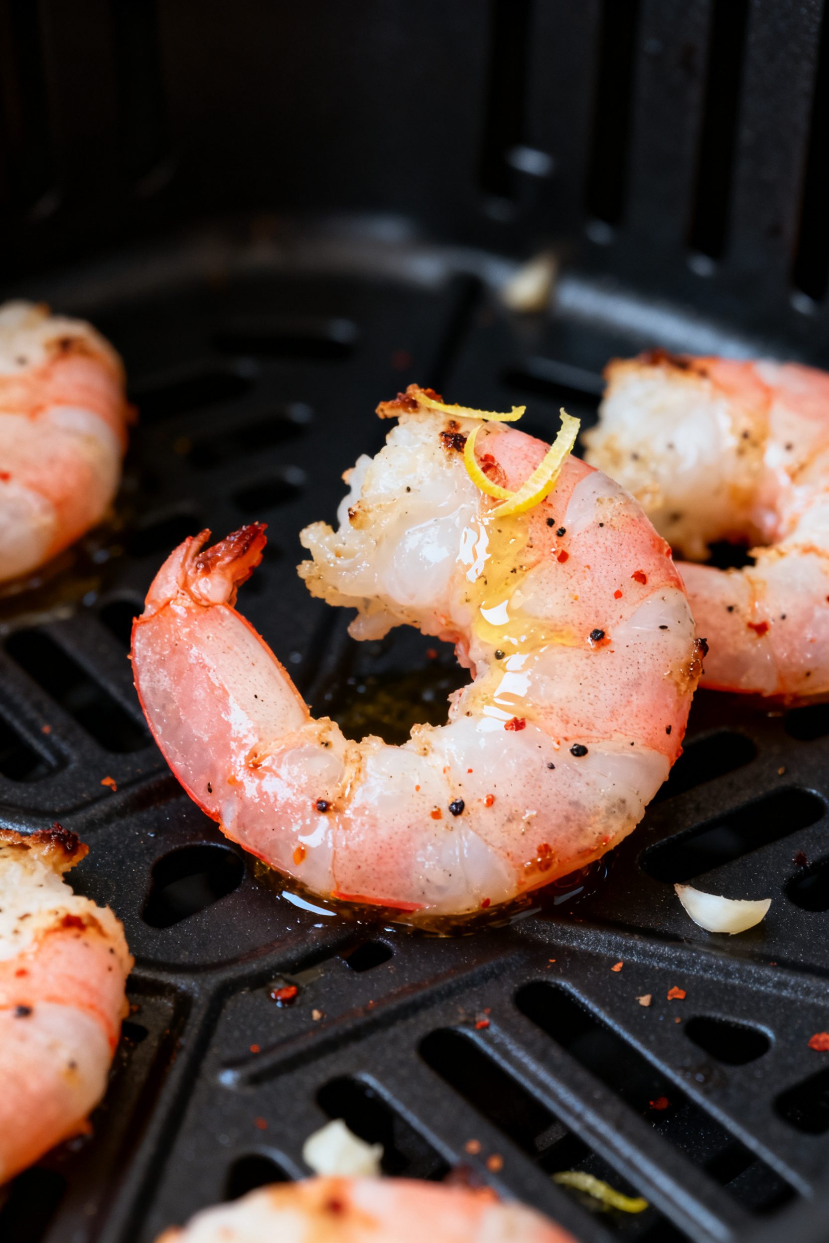 Close-up detail: Air-fried shrimp just out of the basket, pink and opaque with light charred edges a
