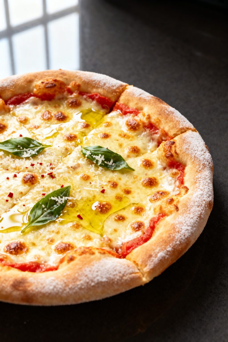Close-up detail: Air fryer mini Margherita pizza just out of the basket, cheese fully melted with go