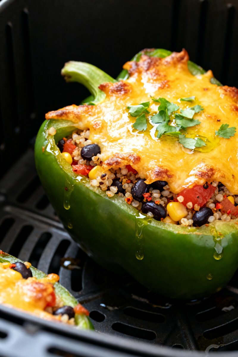 Close-up detail: Air fryer stuffed bell pepper just finished browning in the basket, cheese on top g