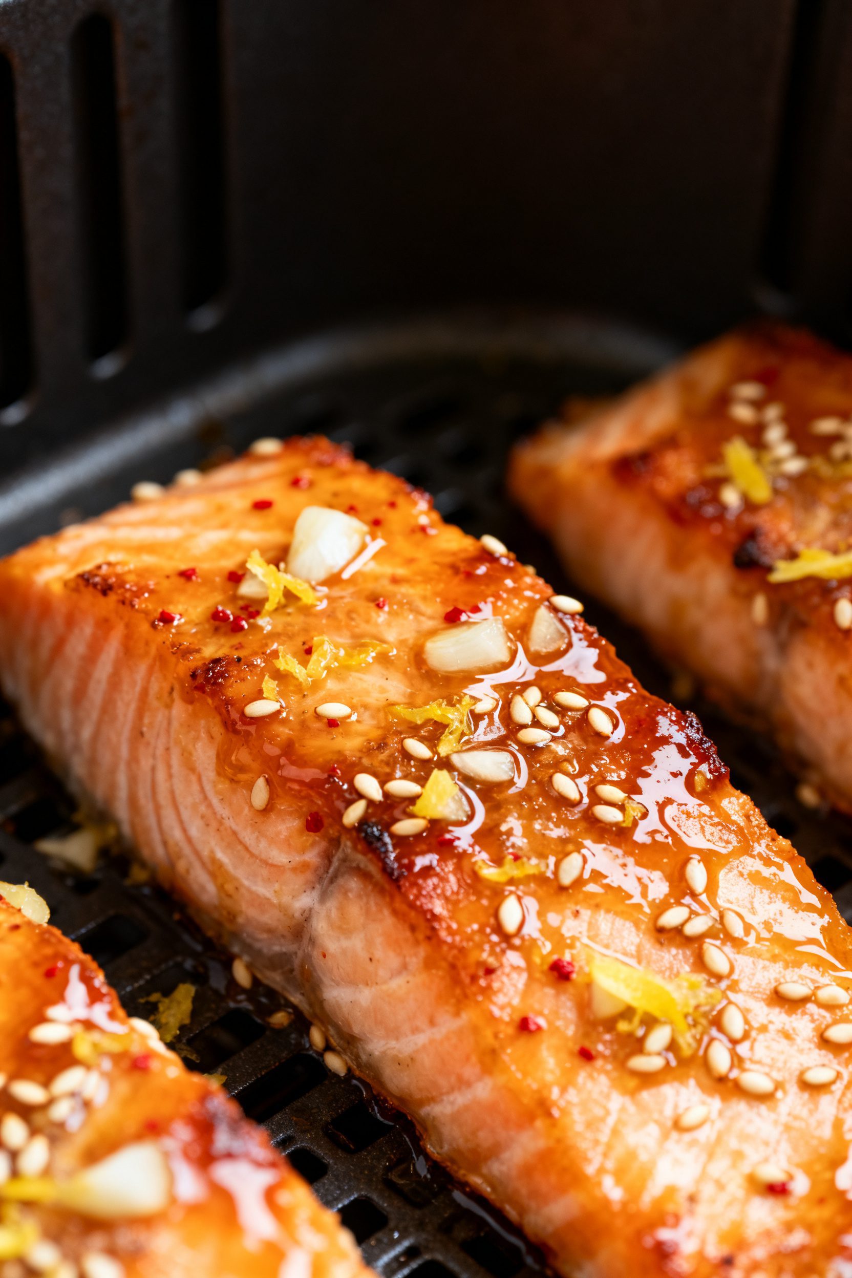 Close-up detail: Glossy air fryer honey garlic salmon fillet just finished cooking, edges lightly ca