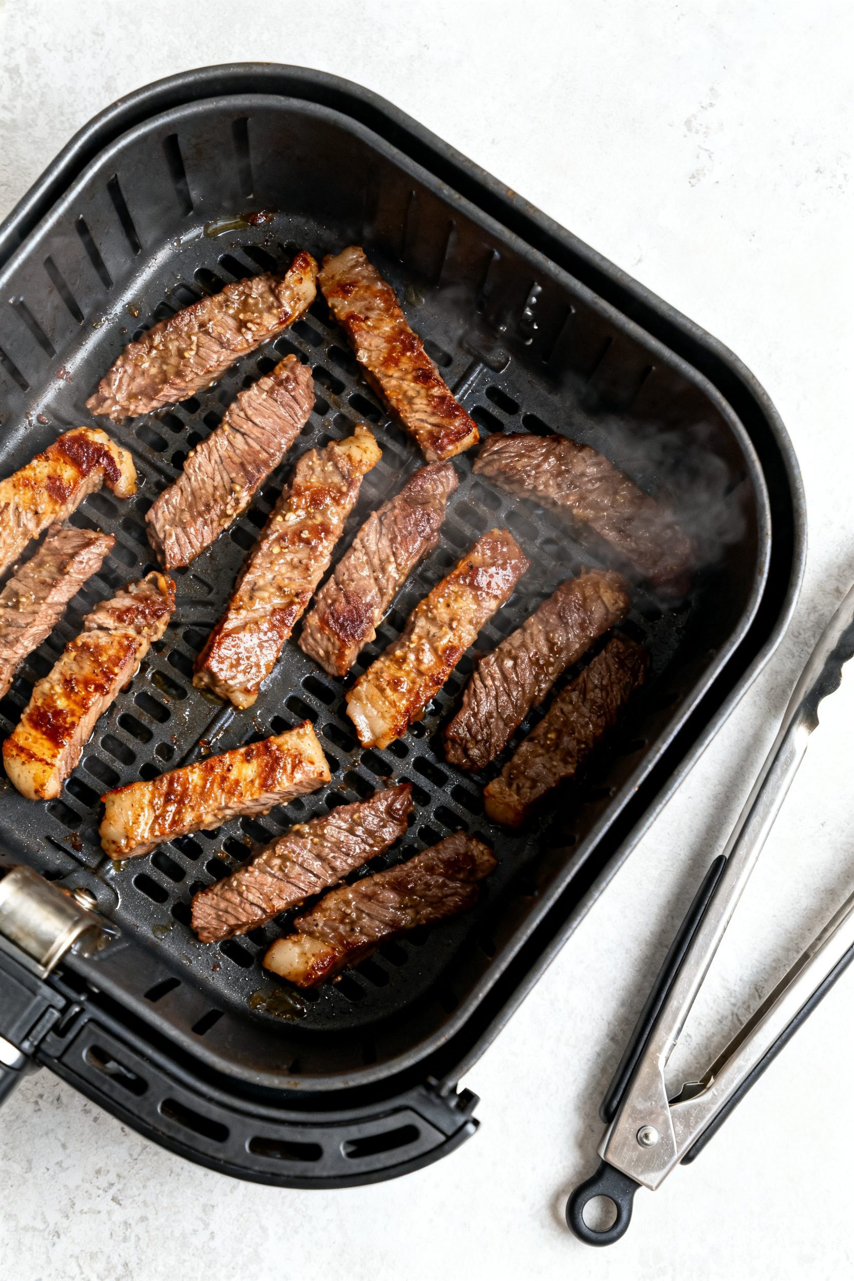 Cooking process: Overhead shot of a single-layer arrangement of coated beef strips in an open air fr