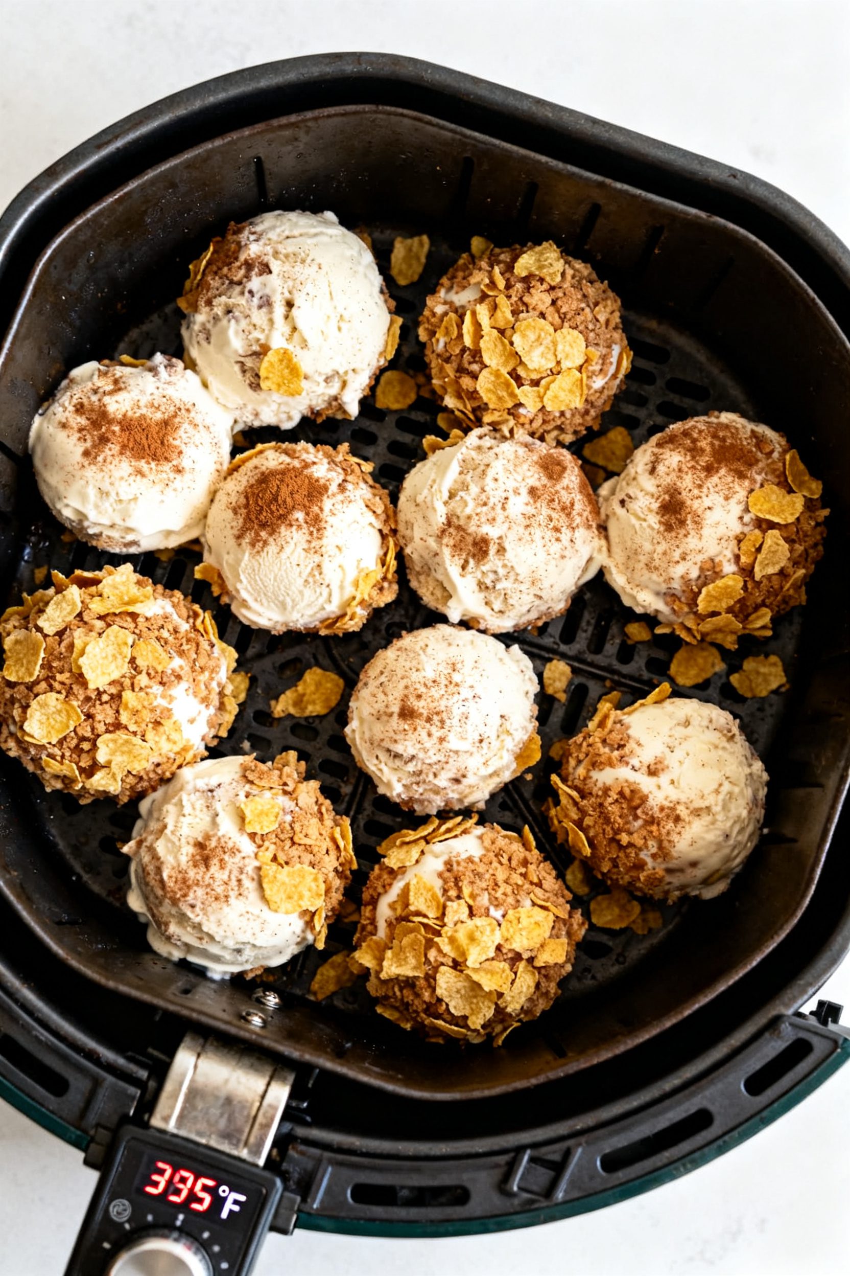 Cooking process: Overhead shot of double-coated ice cream balls arranged in a preheated air fryer ba