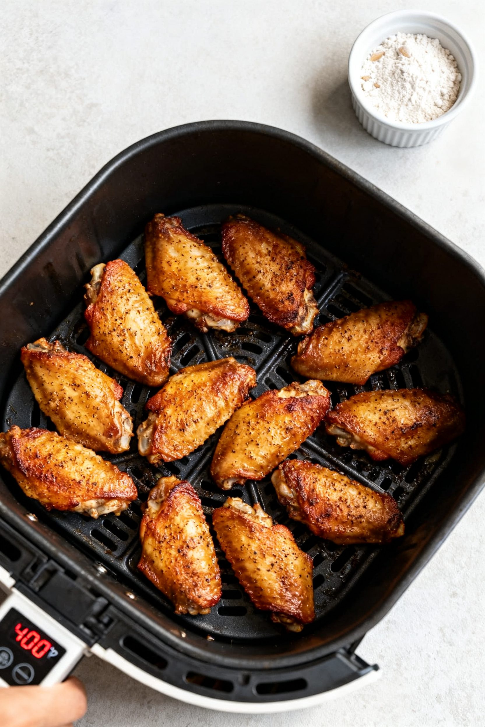 Cooking process: Overhead shot of seasoned wings arranged in a single layer inside an air fryer bask