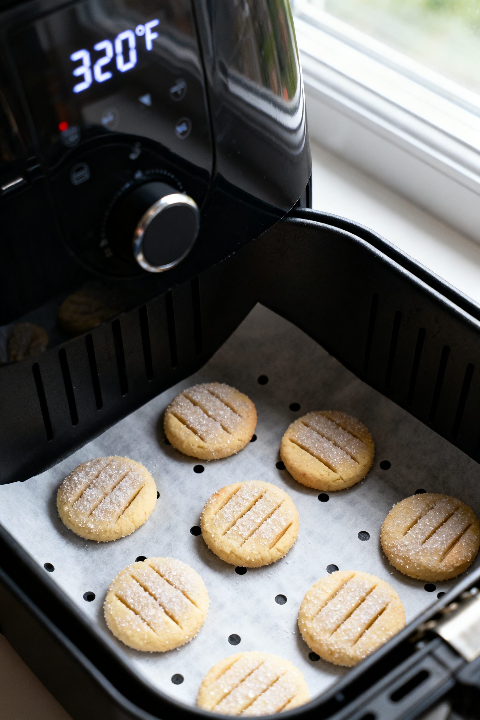 Cooking process: Overhead shot of shaped cookie dough rounds in the air fryer basket, each rolled in