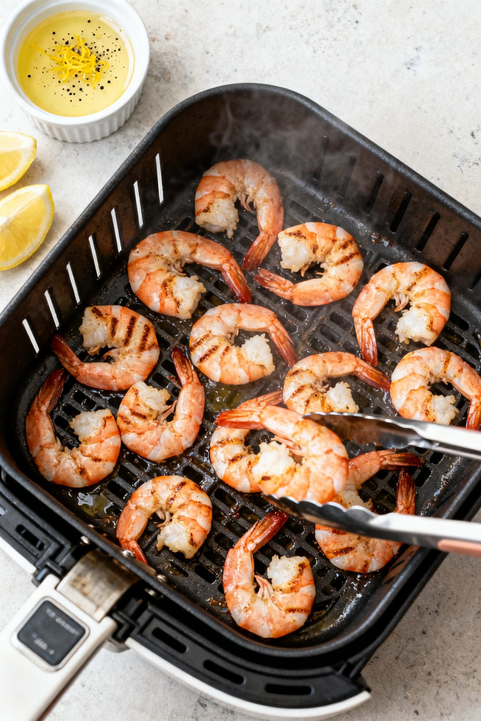 Cooking process: Overhead shot of shrimp arranged in a single layer inside an open air fryer basket 