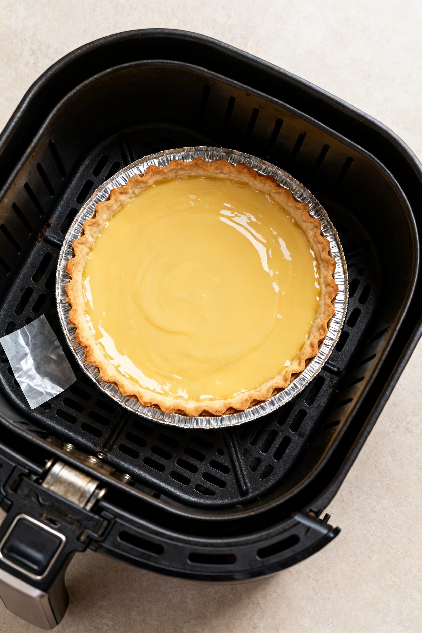 Cooking process: Overhead shot of the pie mid-bake in the air fryer at 325°F, basket pulled out sli