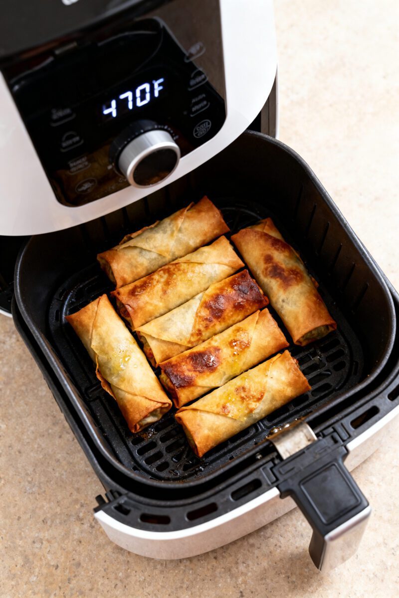 Cooking process shot: Overhead view of an air fryer basket mid-cook with a single, uncrowded layer o
