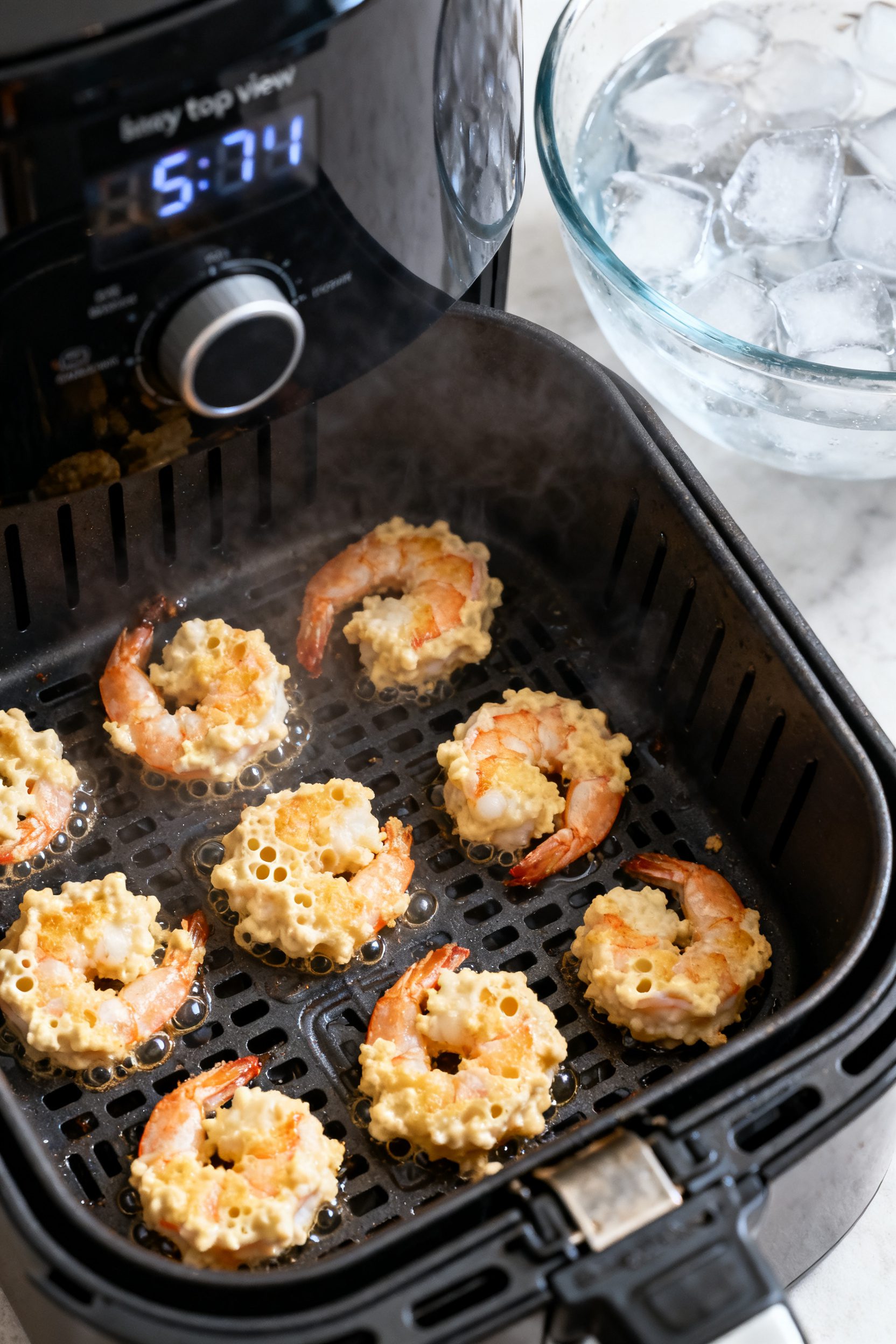 Overhead “tasty top view” of a small-batch cooking scene: a single layer of battered shrimp spac