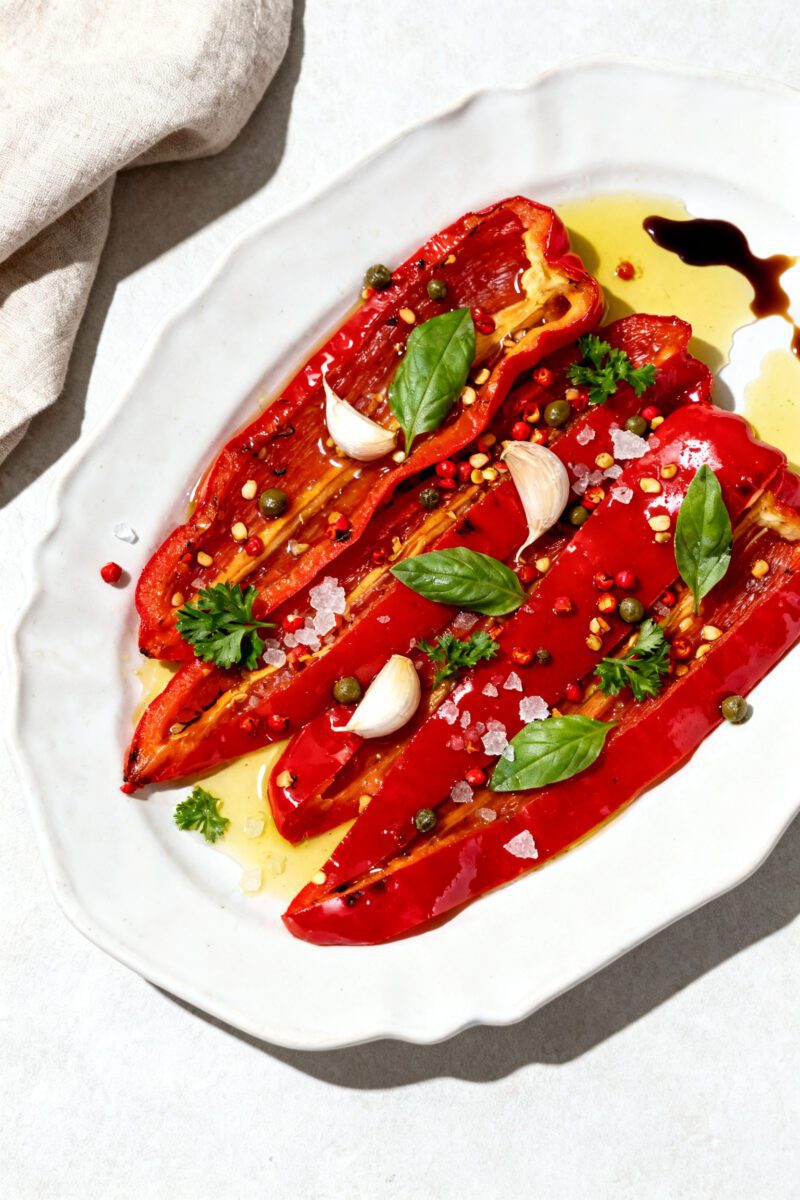 Tasty top view: Overhead shot of peeled, sliced roasted red pepper strips marinating on a white cera